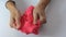 Hands crushing and crumpling pink plasticine with small balls inside, anti stress and relaxing game, close up
