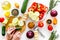 Hands cut different fresh vegetables on cutting board for cooking vegetable stew. White background top view