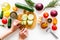 Hands cut different fresh vegetables on cutting board for cooking vegetable stew. White background top view