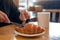 Hands cutting a piece of croissant by fork for breakfast with coffee cup on wooden table