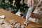 Hands decorating gingerbread cookies with icing and cute dog helping tasting and licking sugar paste on background of christmas