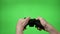 Hands of dedicated young gamer using a game controller with green screen in background -