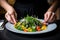 hands delicately arranging salad on a modern plate