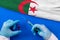 Hands of doctor holding syringe and coronavirus COVID-19 vial vaccine on flag Algeria