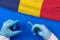 Hands of doctor holding syringe and coronavirus COVID-19 vial vaccine on flag Romania