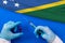 Hands of doctor holding syringe and coronavirus COVID-19 vial vaccine on flag Solomon islands