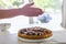 Hands dusting a colorful fig tart with icing sugar in the kitchen