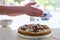 Hands dusting a colorful fig tart with icing sugar in the kitchen