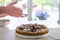 Hands dusting a colorful fig tart with icing sugar in the kitchen