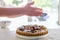 Hands dusting a colorful fig tart with icing sugar in the kitchen