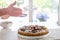 Hands dusting a colorful fig tart with icing sugar in the kitchen