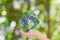 Hands with Earth and recycle logo over green nature background