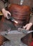 Hands of an elderly blacksmith working iron with a hammer and th