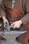 Hands of an elderly blacksmith working iron with a hammer and th