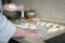 The hands of an elderly cook sculpt dough blanks for a pie