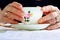 Hands of elderly lady holding a delicate bone china cup. Concept of Mother`s Day. Concept of aging and elderly care