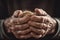 Hands of an elderly man holding ears of wheat, close-up, dark background