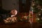 Hands of an elderly man holding a shot glass alone at a table with Christmas decoration, cookies, candle and a half-empty bottle