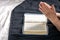 The hands of an elderly woman folded in prayer in front of a book of the Bible.