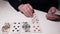 The hands of an elderly woman lay out fortune-telling cards on the table. Solitaire, divination