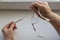 Hands of elderly woman leaning on white windowsill hold thermometer with high temperature readings and glasses in beige frames