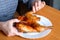 The hands of an elderly woman operate a grilled chicken