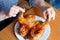 The hands of an elderly woman operate a grilled chicken