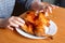 The hands of an elderly woman operate a grilled chicken