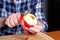 The hands of an elderly woman peel a red ripe tasty juicy apple