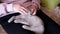 Hands of an Elderly Woman Stroking a Small Gray Kitten Sitting on Knees. Zoom
