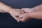 Hands of elderly and young women on black background