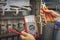 Hands of electrician with multimeter and nippers close-up on background of electric control cabinet for industrial equipment