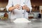 Hands of a female chef breaking an egg into a heap of measured flour while making dough.