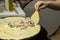 Hands of female chef cooking a salty crepe with mushrooms, stewed chicken