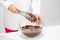 Hands of Female chocolatier mixing melted dark chocolate with whisk isolated