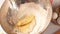 Hands female confectioner mixing crumbs and whipped cream in mixing bowl, close up.