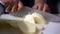 Hands of female cook slowly slicing a potato