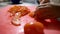 Hands of female cook slowly slicing a tomato