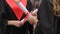 Hands of female graduates holding diplomas tied with red ribbons, conversation