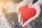 Hands female holding red heart on nature background