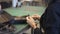 Hands of female leather worker tying up thread on black detail in workshop.