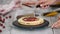 Hands of female pastry chef making delicious cake of layers, whipped cream and berry jam using rotating cake stand