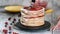 Hands of female pastry chef making delicious cake of sponge layers, whipped cream and berry jam using rotating cake