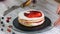 Hands of female pastry chef making delicious cake of sponge layers, whipped cream and berry jam using rotating cake