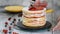 Hands of female pastry chef making delicious cake of sponge layers, whipped cream and berry jam using rotating cake