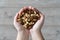 Hands filled with mixed almonds on a bright background.