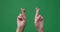 Hands with fingers crossed over green screen