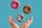 Hands and flying donuts on a blue background, junk food concept