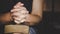 Hands folded in prayer on a Holy Bible in church concept for faith