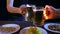 The hands of friends at the bar hit beer mugs together on a black background